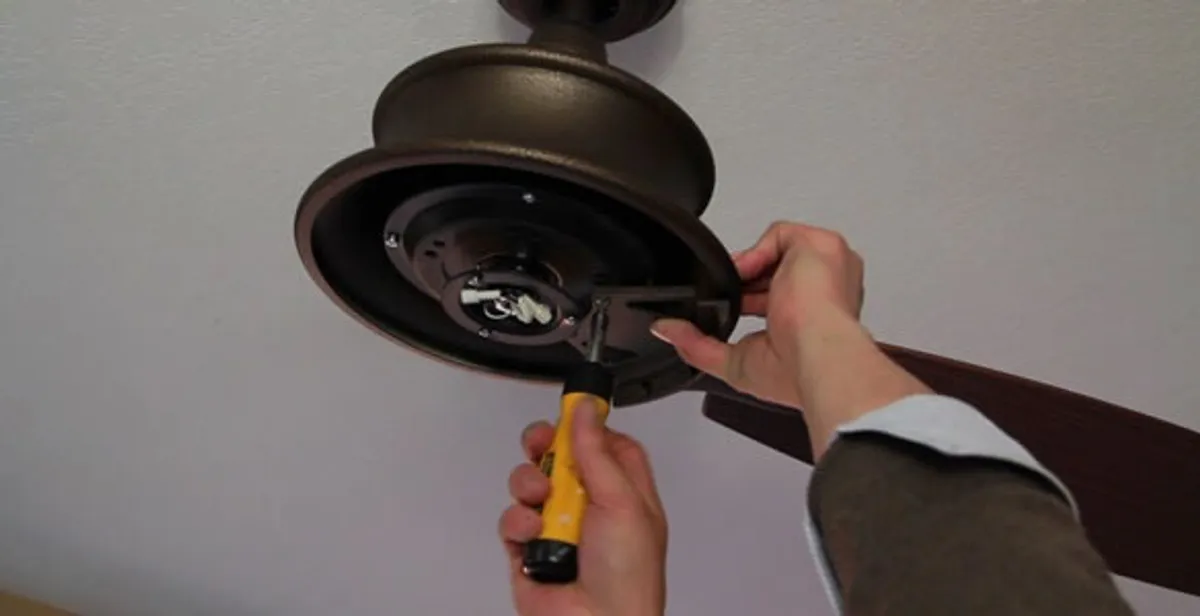 Electrician installing ceiling fan mounting bracket and fixture in Austin, TX